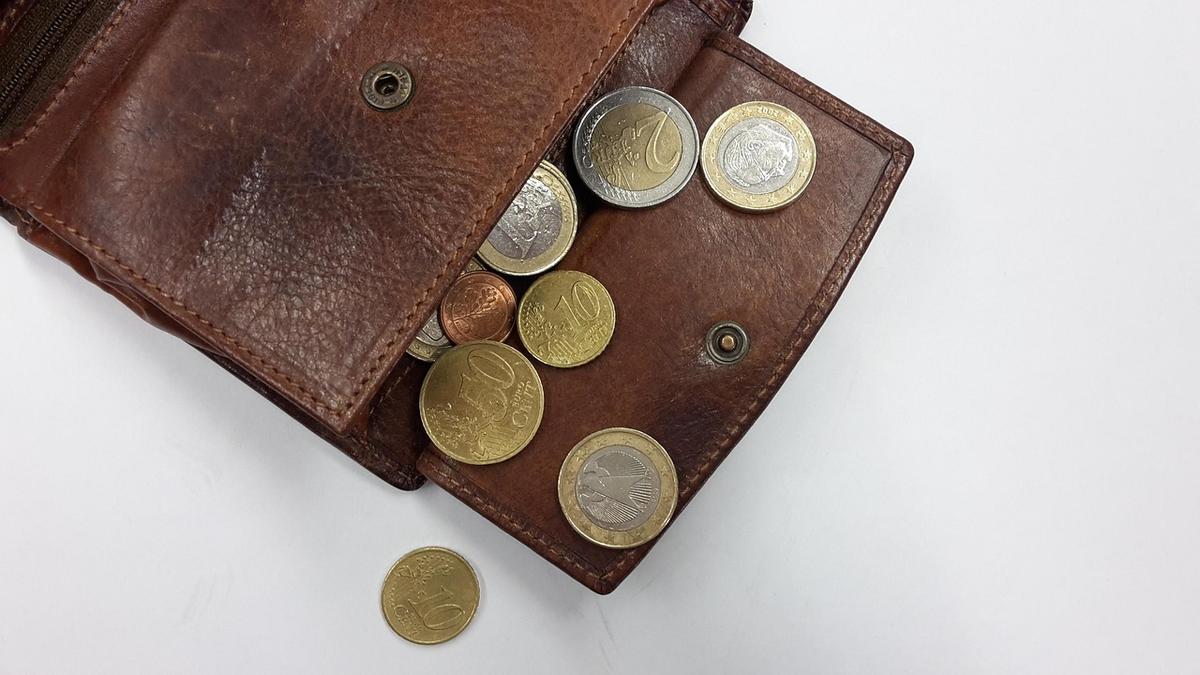 A pair of hands carefully allocating stylized glowing currency into clearly labeled glass jars representing savings, investments, and essential expenses, on a pristine, organized desk, illustrating strategic budget management and financial stability.
