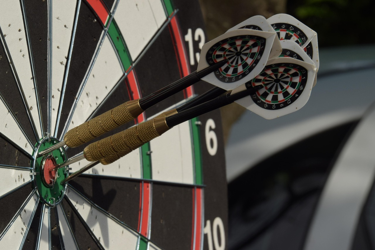 A detailed financial blueprint on a desk, with a hand pointing to clearly marked short-term and medium-term goals leading along a path towards a large, illuminated bullseye target in the distance, symbolizing foundational financial planning and strategic goal setting.