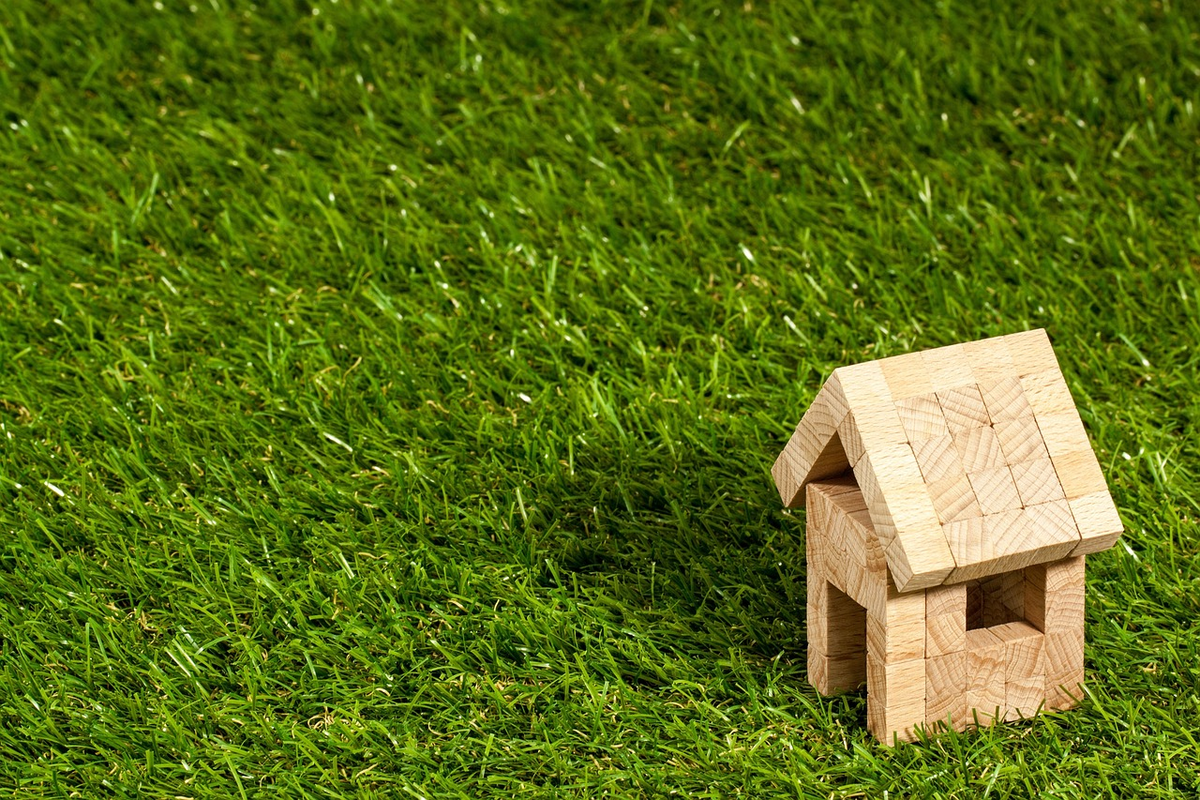 A miniature house resting securely on a foundation of ascending financial graph lines and scattered currency, vividly portraying real estate as a stable and continuously appreciating investment.