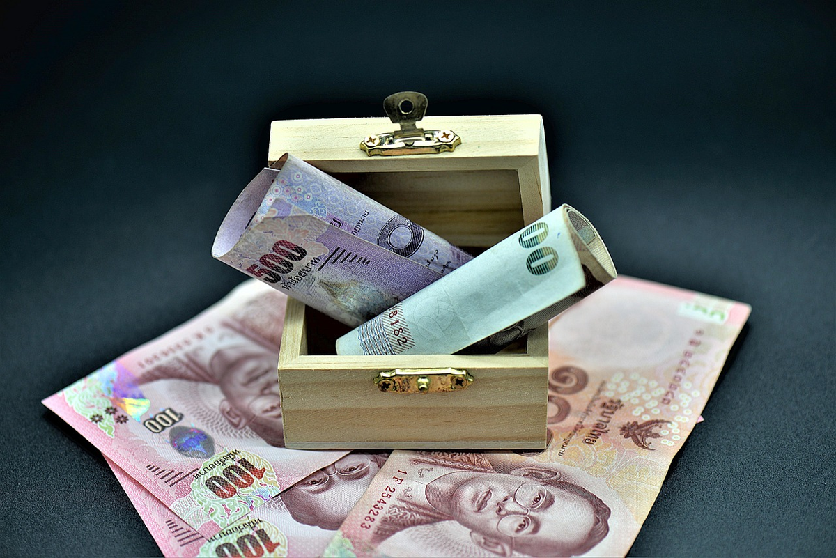 Hands actively interacting with various financial tools on a clean surface, including a tablet displaying a detailed budget spreadsheet, a physical ledger with a pen, and neatly stacked coins and banknotes, symbolizing practical money management and the foundation of financial planning.