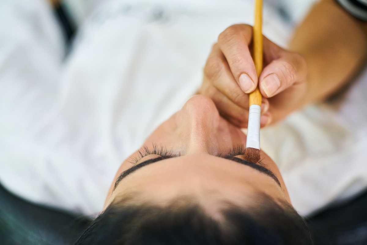 A close-up of a hand meticulously filling out a financial application form with a pen, emphasizing the careful precision and detailed data entry required for official financial processes and regulatory compliance.