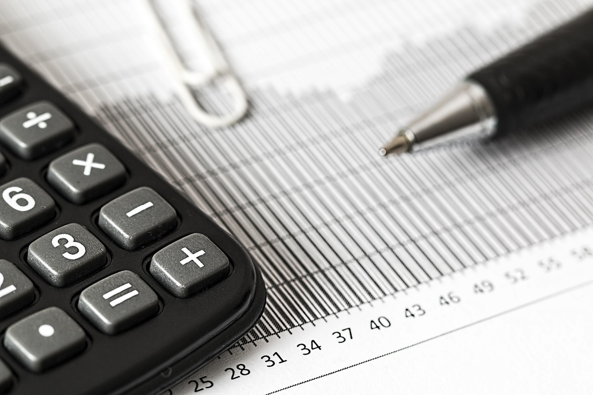 A single, focused hand carefully positions the first building block on a blueprint illustrating a financial growth plan, symbolizing the foundational steps of a beginner investor's journey.