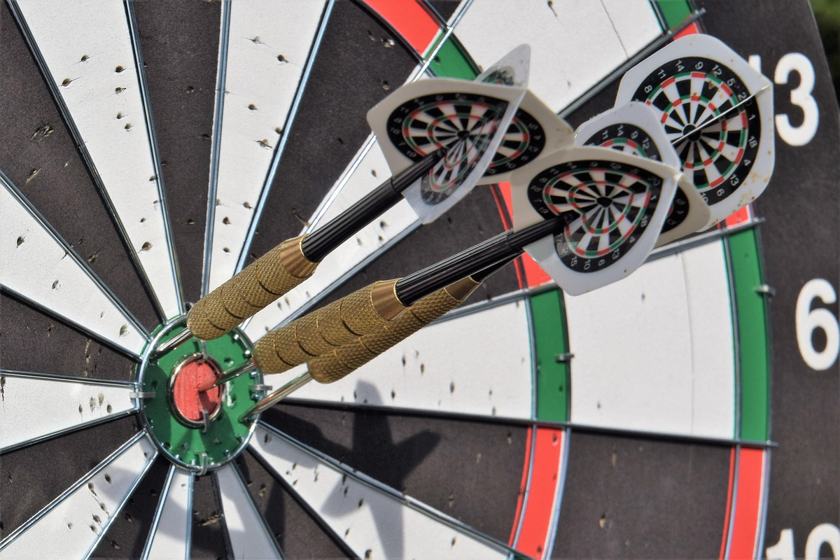 A focused hand precisely aiming a dart at a financial target board, where the concentric rings are labeled with distinct short-term, medium-term, and long-term financial goals, subtly incorporating currency symbols to emphasize purposeful and decisive investment planning.